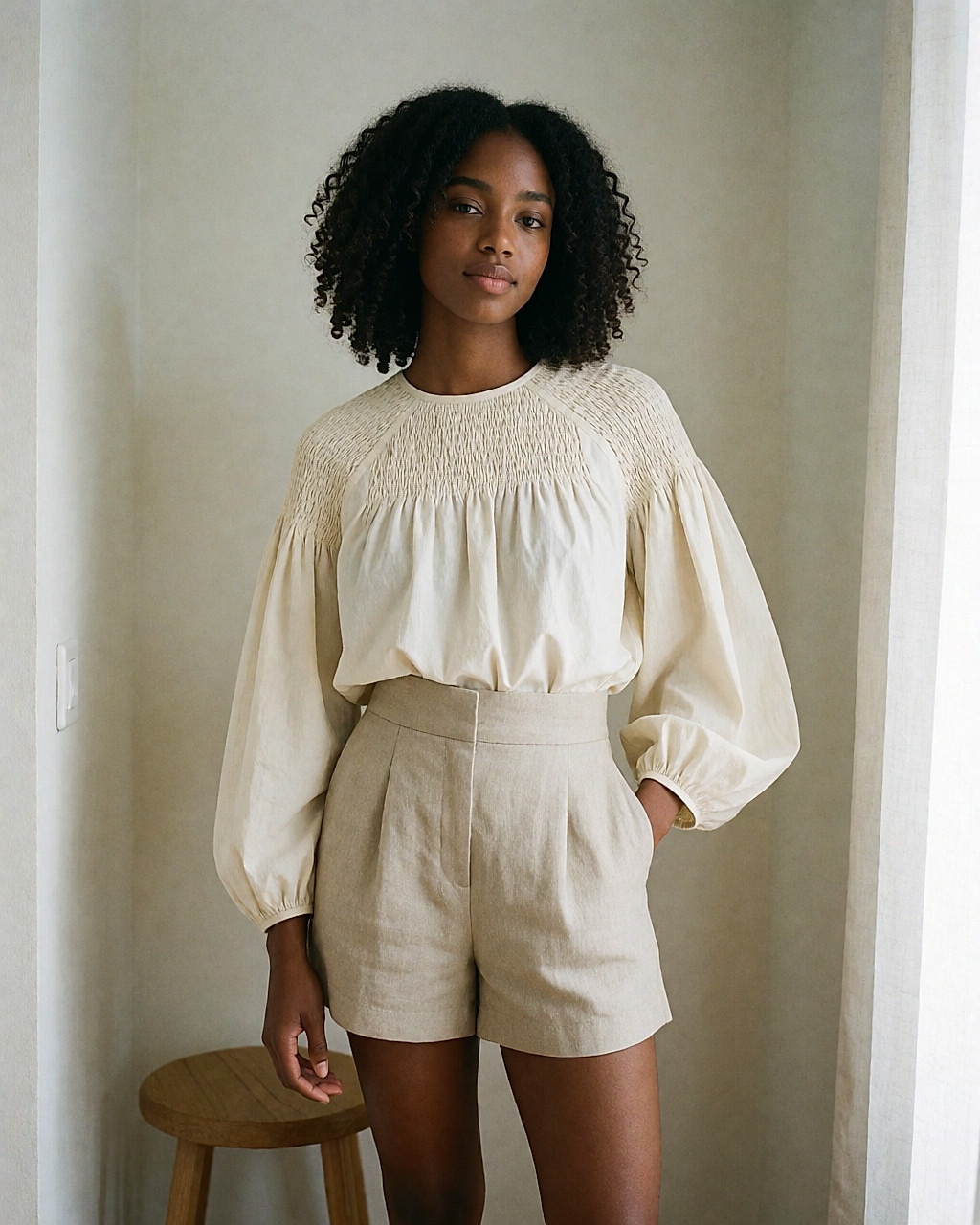 Young woman in high-waisted linen shorts and a cream smocked blouse with balloon sleeves
