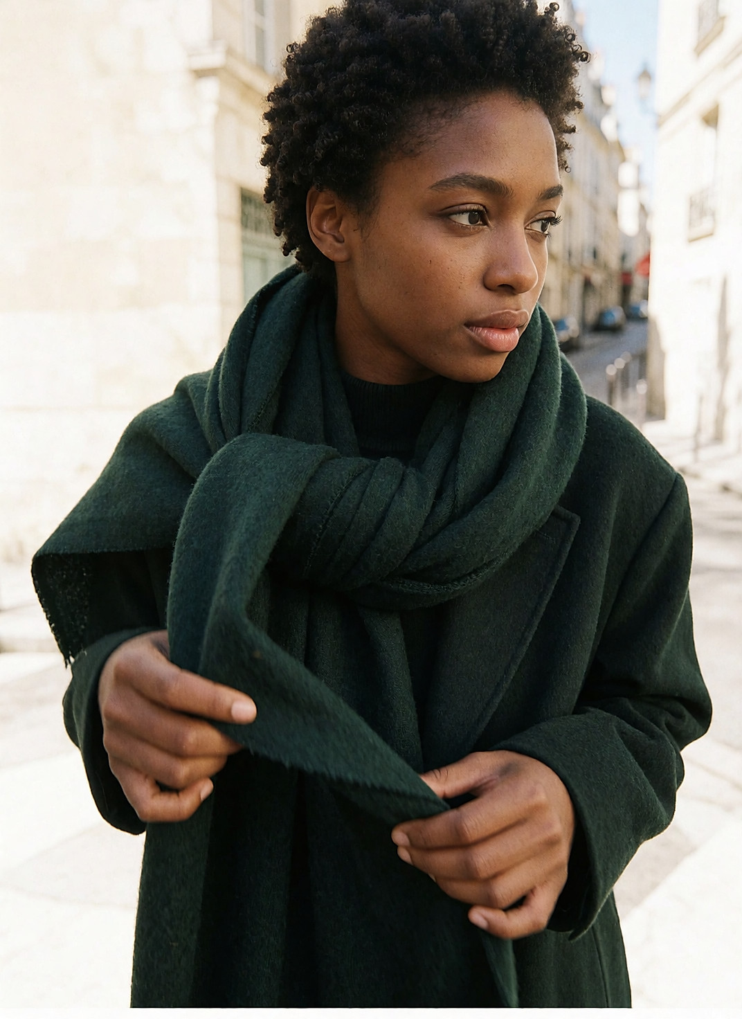 Jeune femme noire nouant une longue écharpe verte en laine mérinos sur son manteau