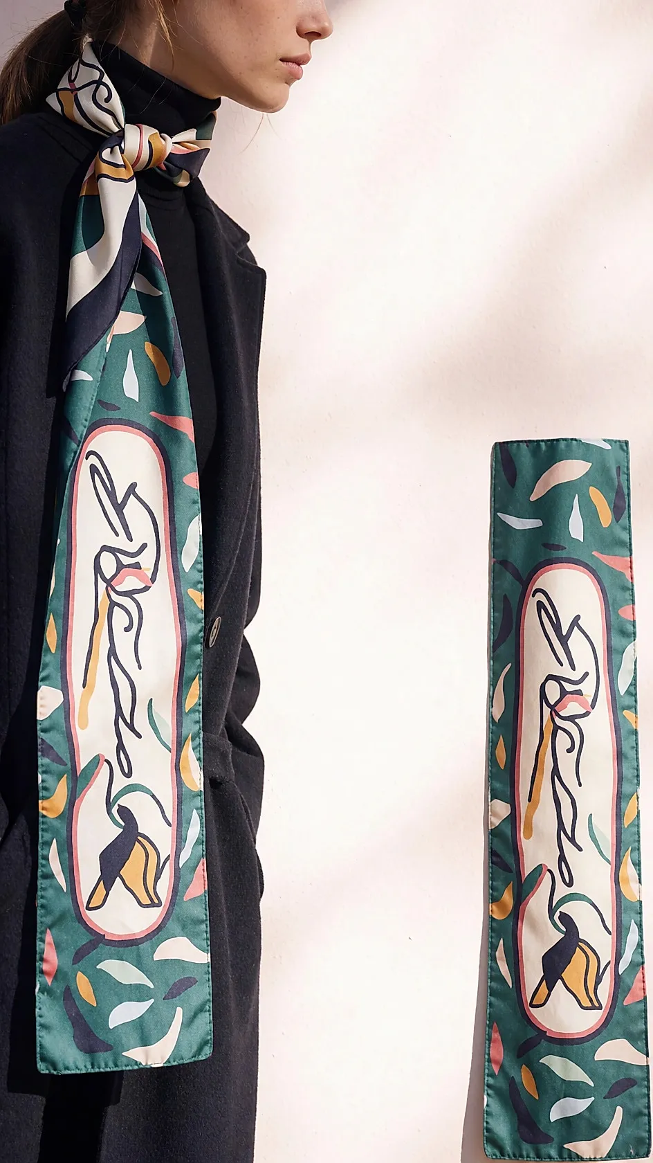 Pañuelo de seda estampado atado como bandana sobre un cuello alto negro