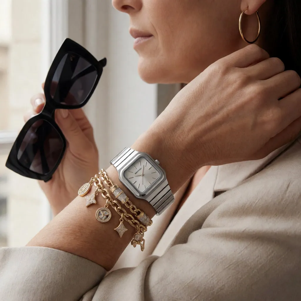 Handgelenk einer Frau mit Stahluhr, Bettelarmbändern und schwarzer Sonnenbrille