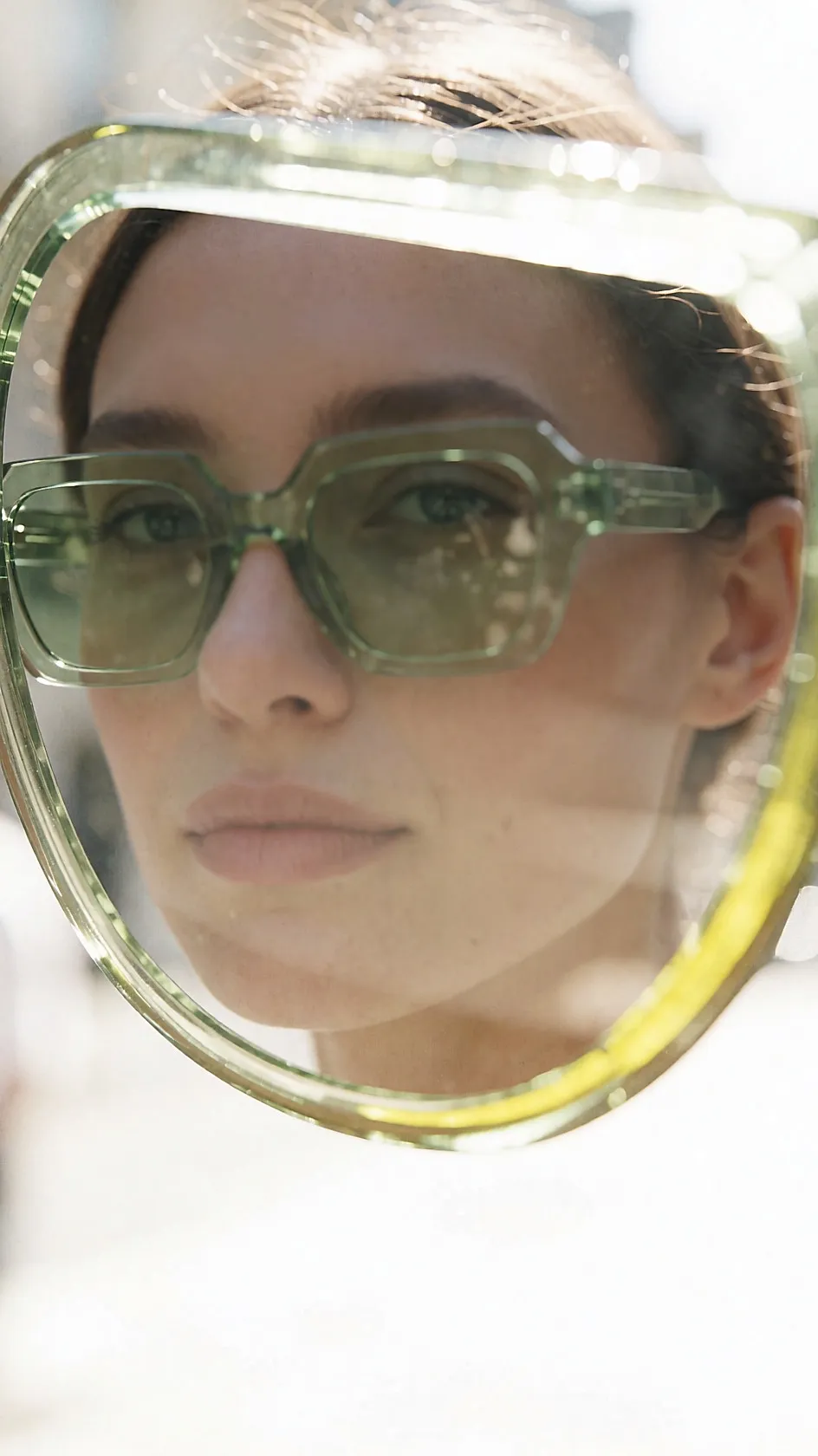 Junge Frau mit Sonnenbrille aus leuchtend grünem Acetat in sonniger Straße
