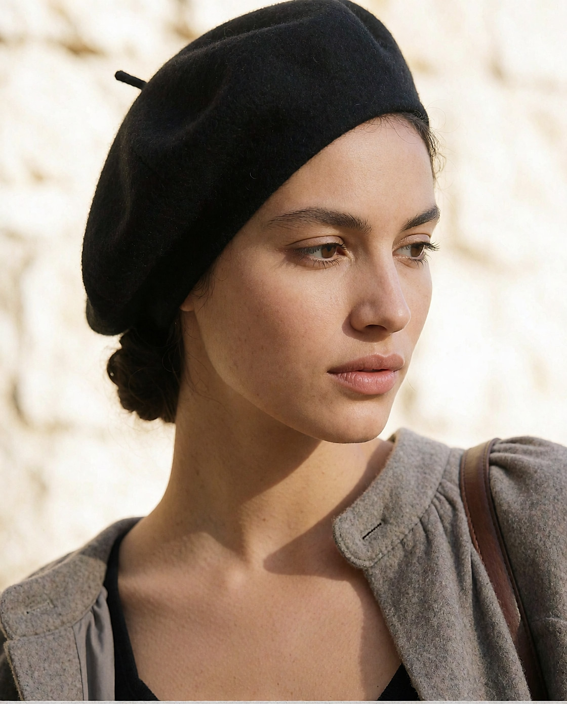 Béret en laine noire porté incliné sur des cheveux attachés, portrait de trois-quarts