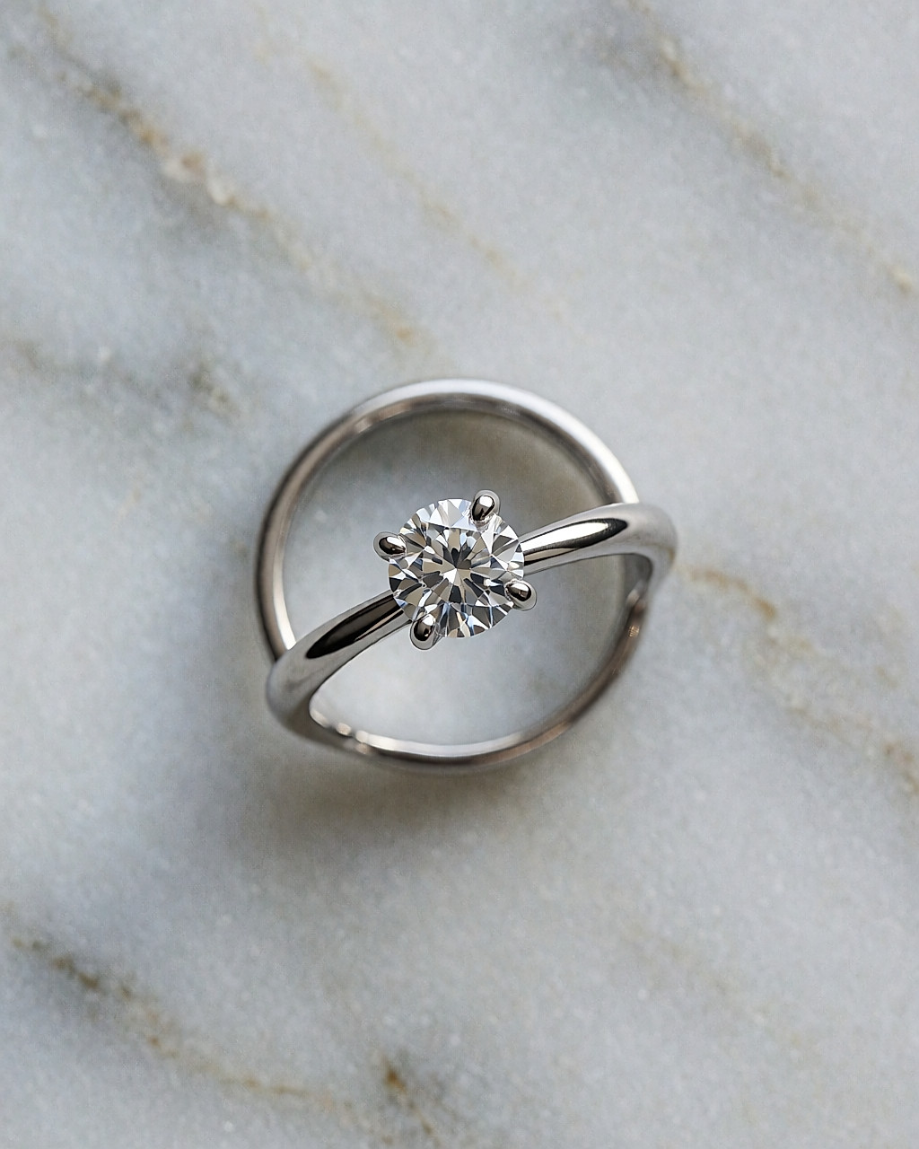 Solitaire en platine au diamant rond vu de dessus sur un marbre gris clair