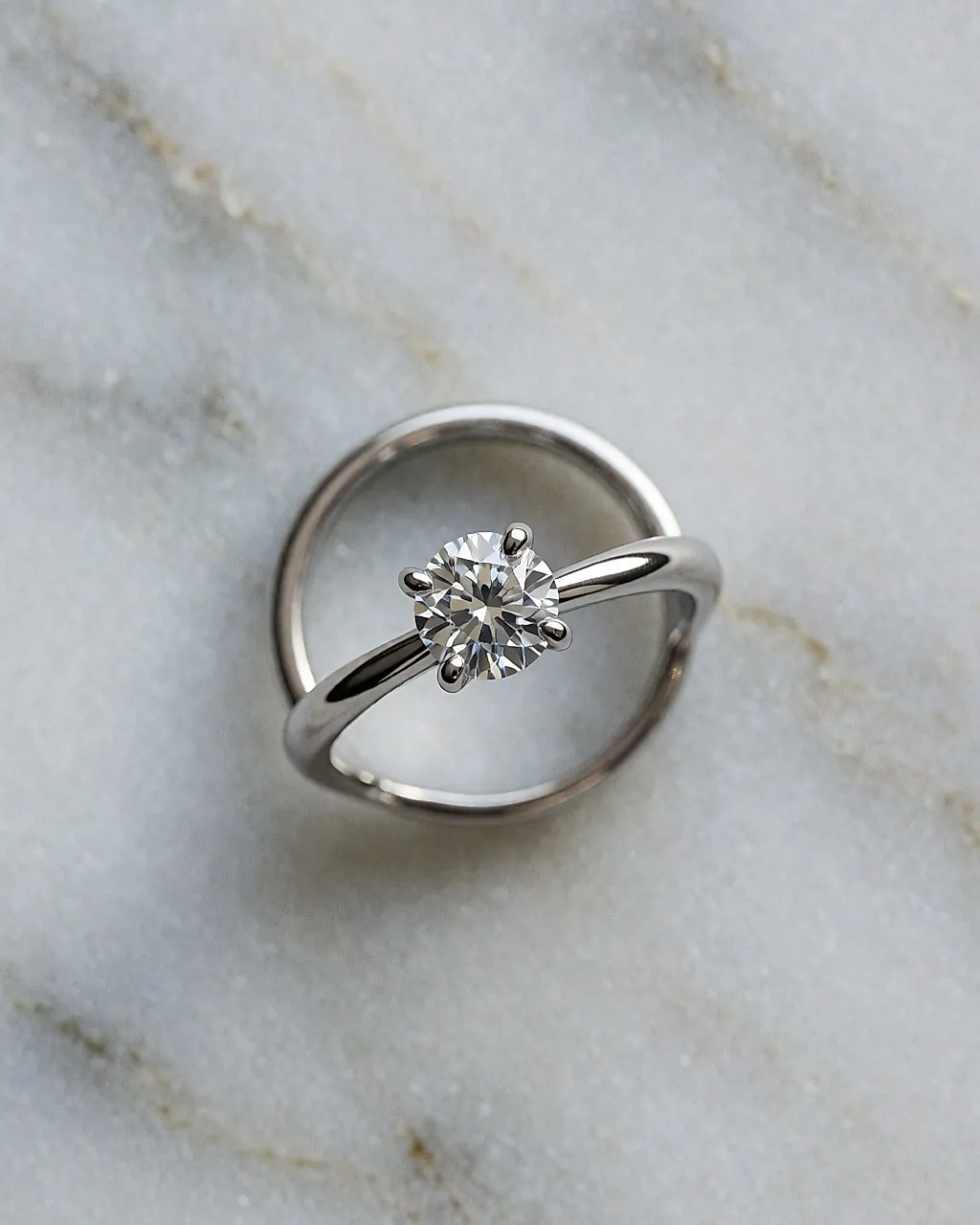 Platin-Solitär mit rundem Diamanten von oben auf hellgrauem Marmor