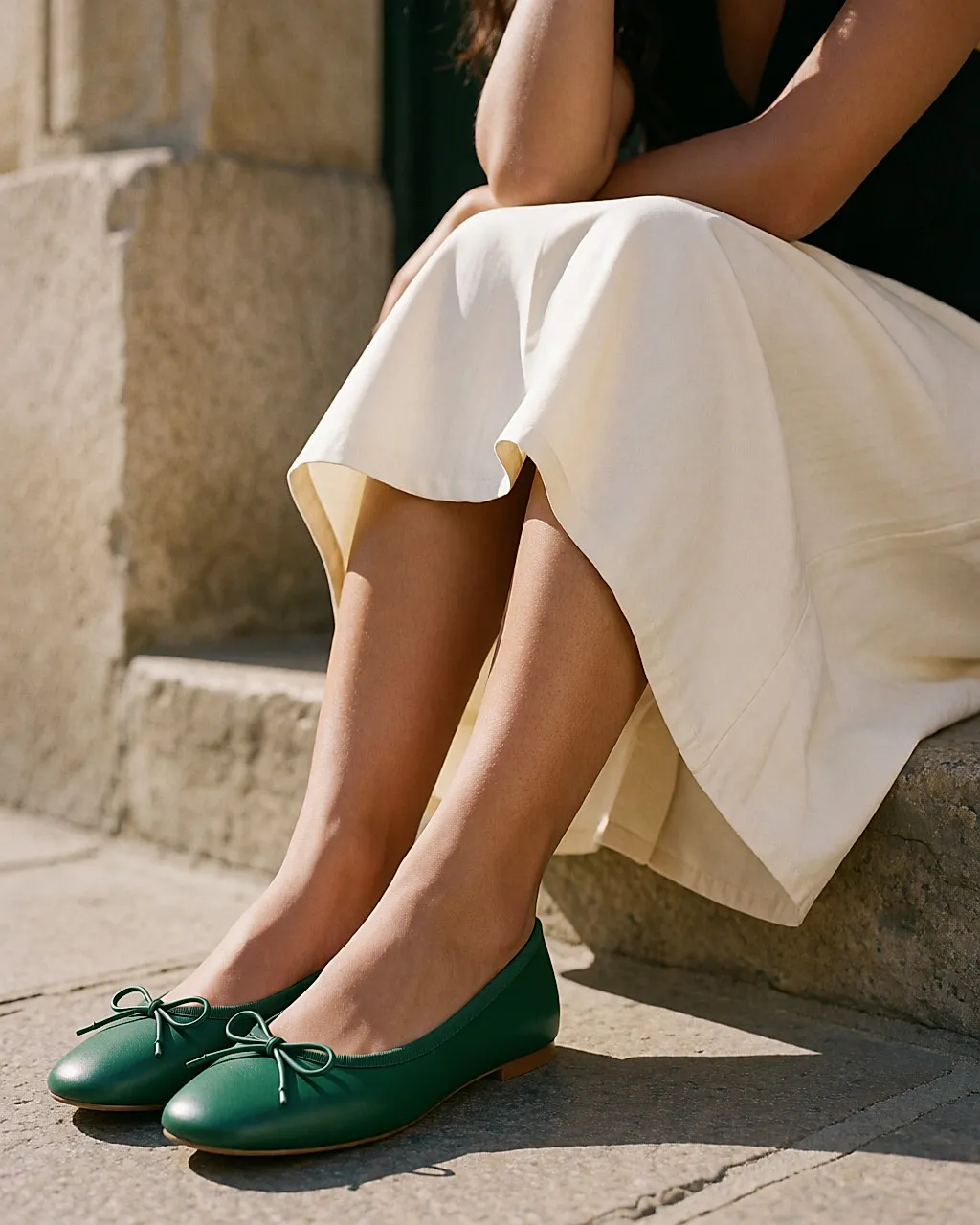 Grüne Ballerinas mit kleiner Schleife an einer draußen sitzenden jungen Frau