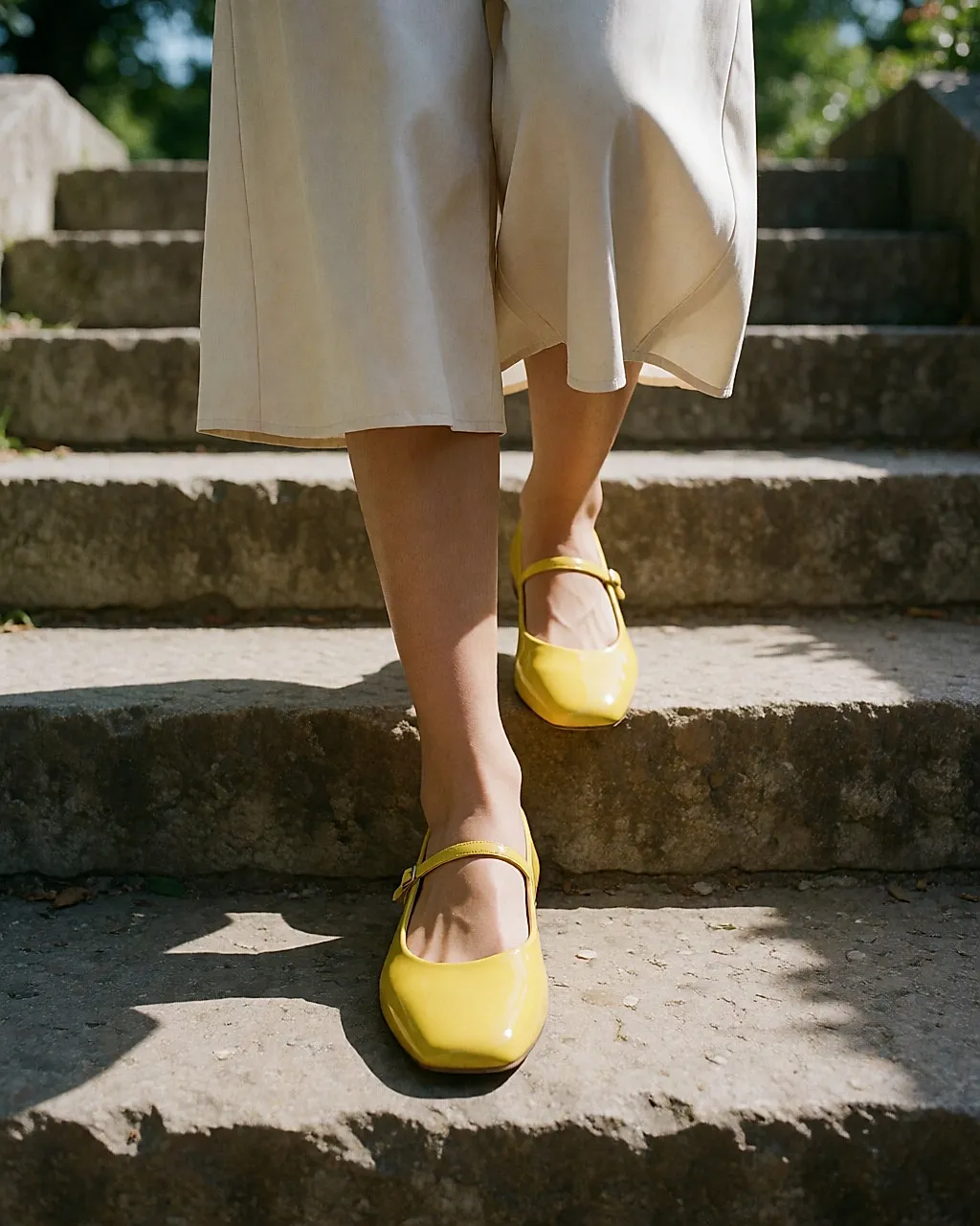 Junge Frau geht eine Steintreppe hinunter, leuchtend gelbe Lackballerinas
