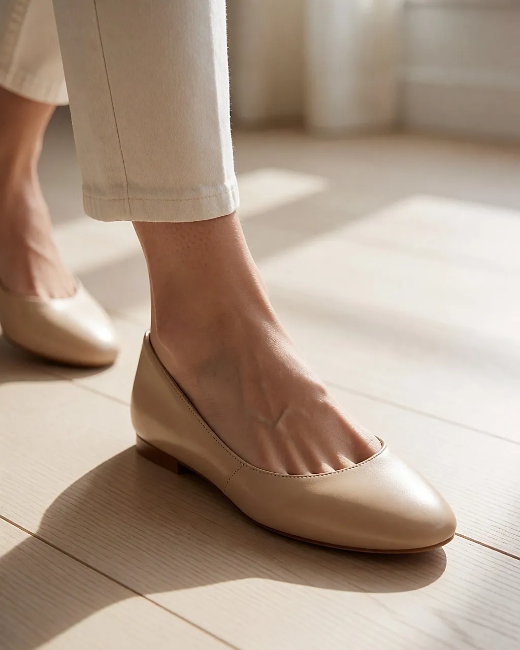 Detail eines Schritts: beige Lederballerinas mit Mandelspitze auf hellem Parkett