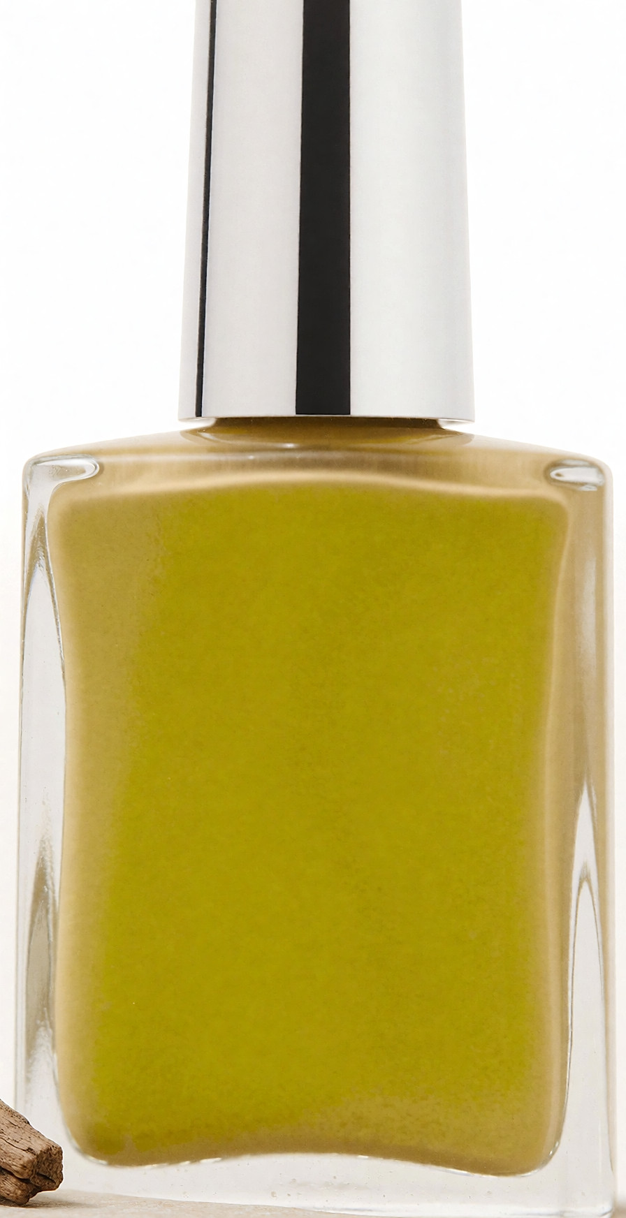 Flacon de vernis beige sable posé sur une pierre claire à la lumière naturelle