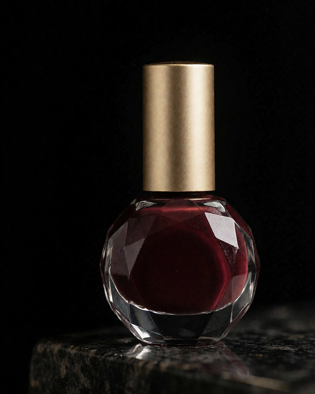 Flacon rond à facettes et bouchon doré rempli d'un vernis bordeaux prune profond