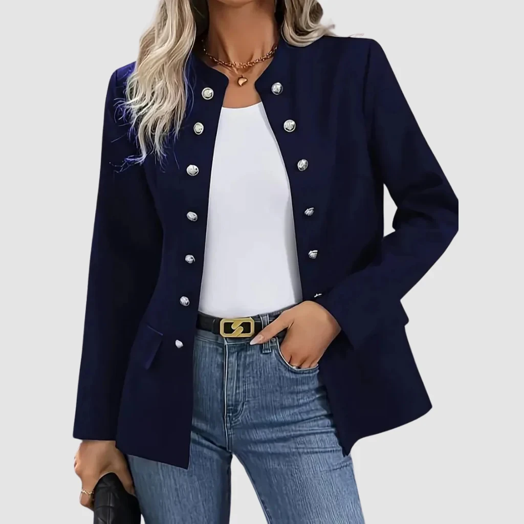 Latina-Schwangere in der Umkleide: fließendes Kleid in Salbeigrün unter strukturiertem beigem Blazer, Dreiviertelansicht im Spiegel
