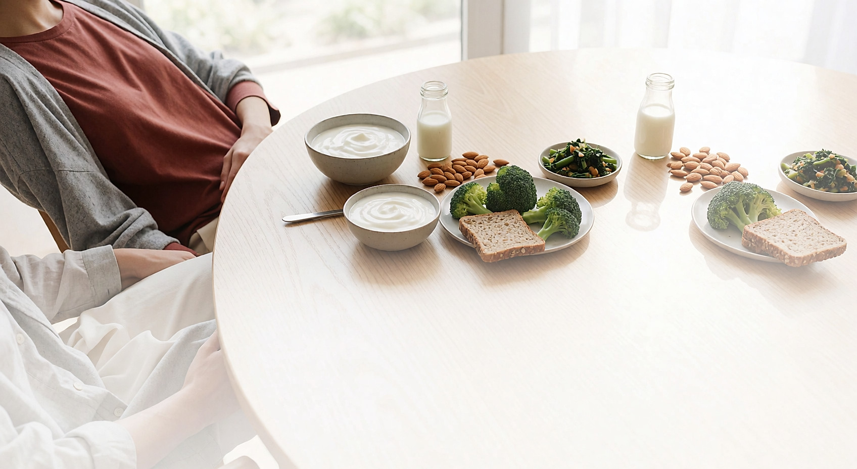 Bol de yaourt nature, petite bouteille de lait, amandes, brocoli et légumes verts