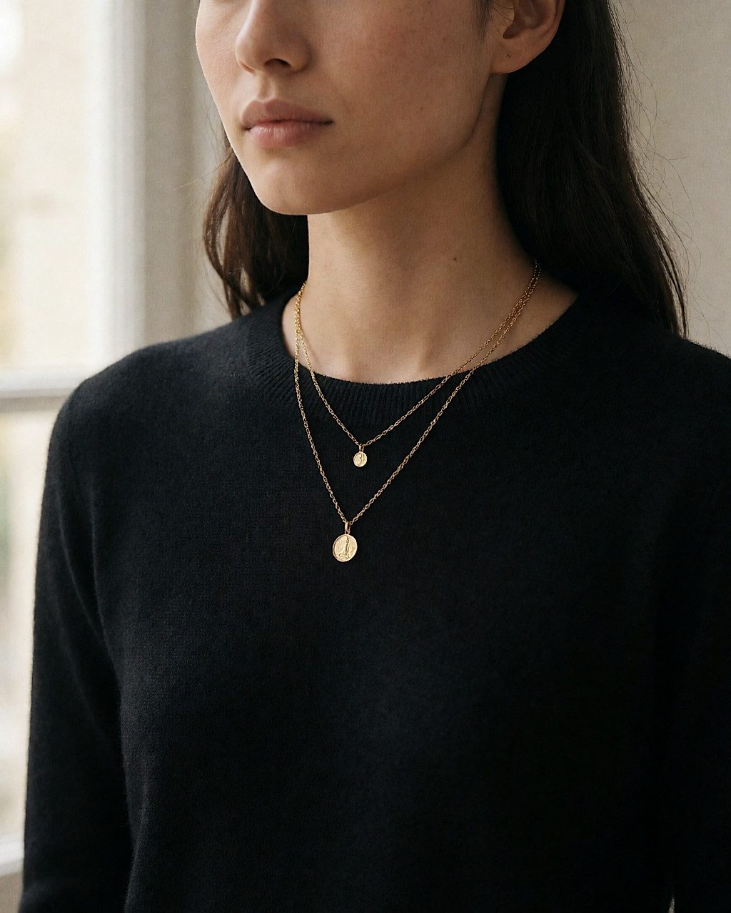 Two fine gold-tone chains of different lengths layered over a black knit