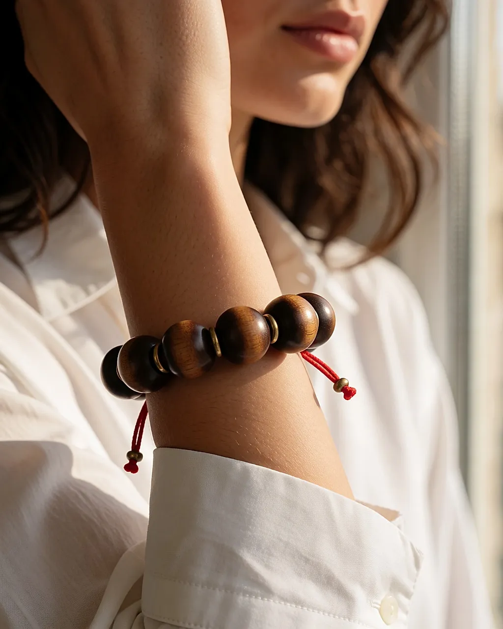 Ethnic wooden and brass bracelet worn on a wrist, white shirt sleeve