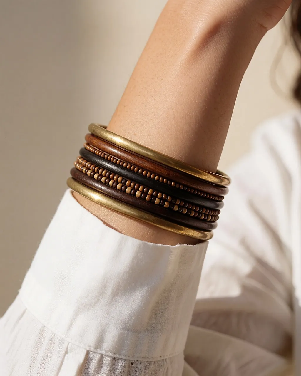 Forearm wearing a stack of fine ethnic bracelets in brass and wood