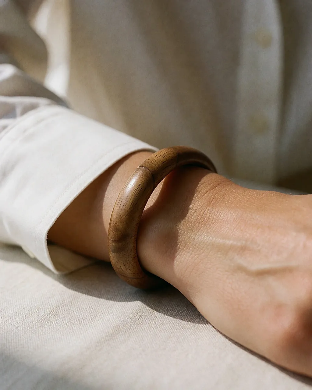 Wrist wearing a turned-wood cuff bracelet over a white shirt sleeve