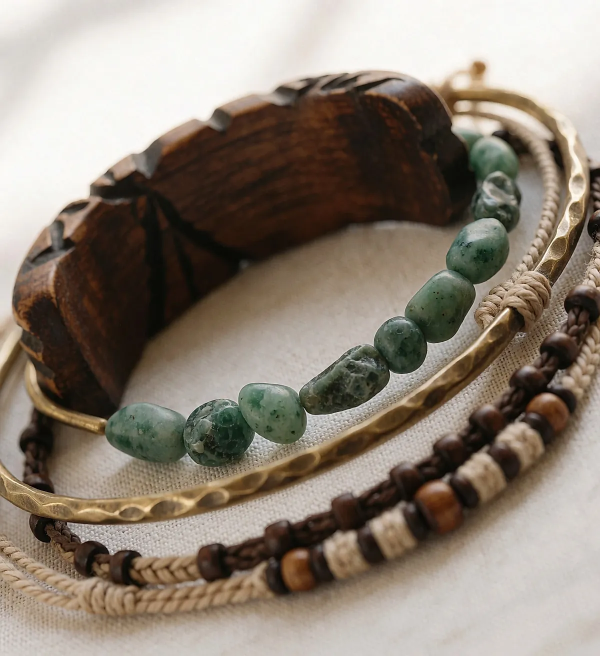 Four ethnic bracelets in turned wood, raw stone, brass and cotton on pale linen