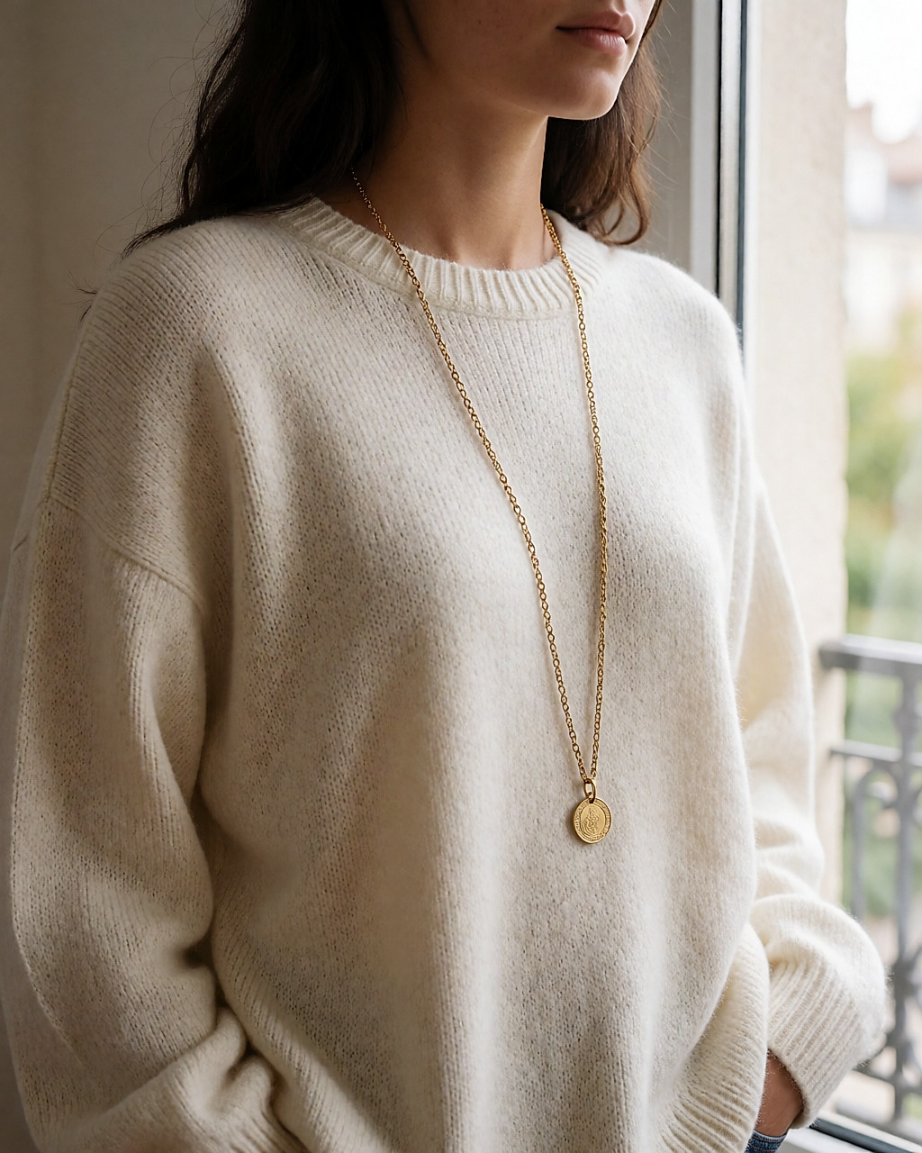 Long sautoir doré à pendentif médaille porté sur une maille ivoire oversize