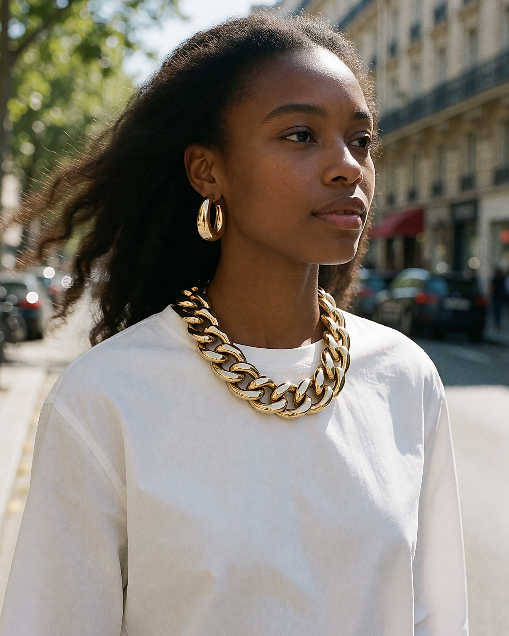 Jeune femme en street style portant une chaîne dorée fine plaquée or et des créoles discrètes