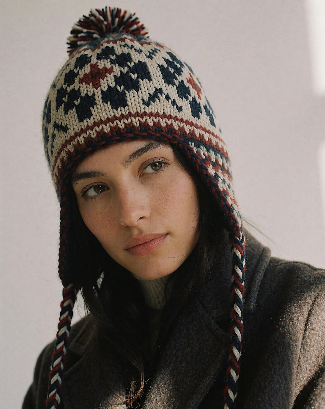 Jeune femme de profil portant un bonnet péruvien à motifs tricotés, pompon et cordons tressés