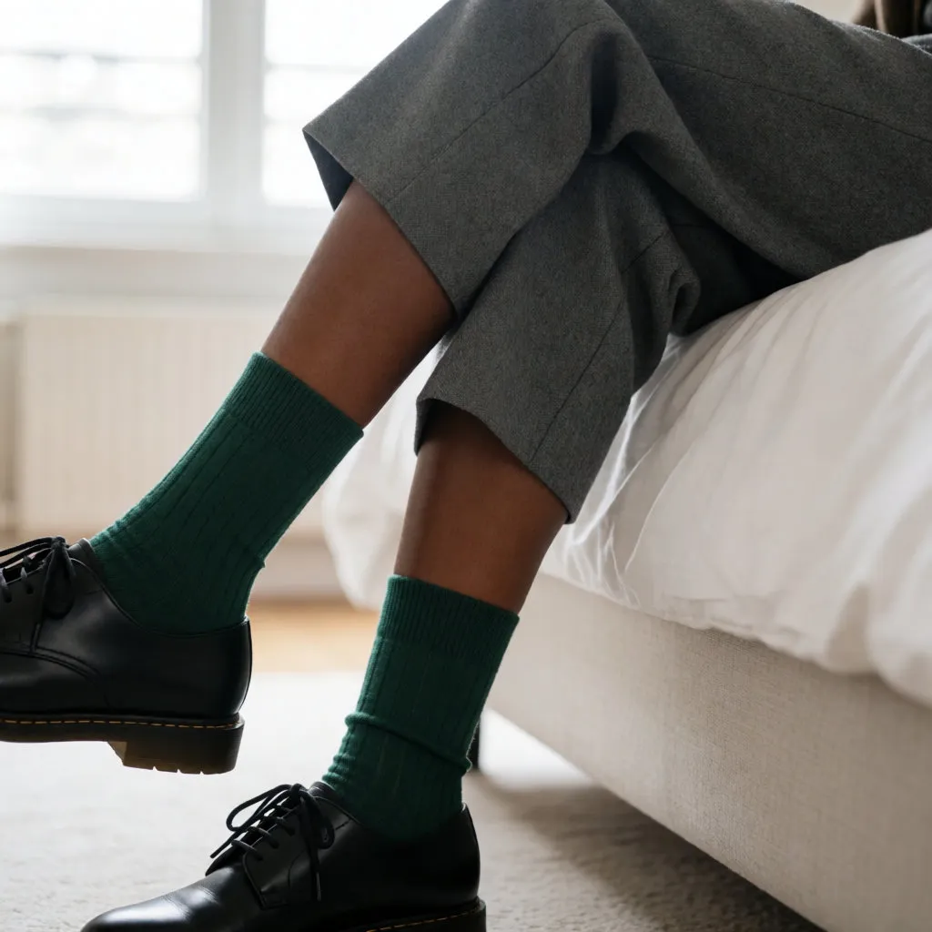 Beine einer jungen Schwarzen Frau mit tannengrünen, gerippten hohen Socken, Derby-Schuhen und verkürzter Hose