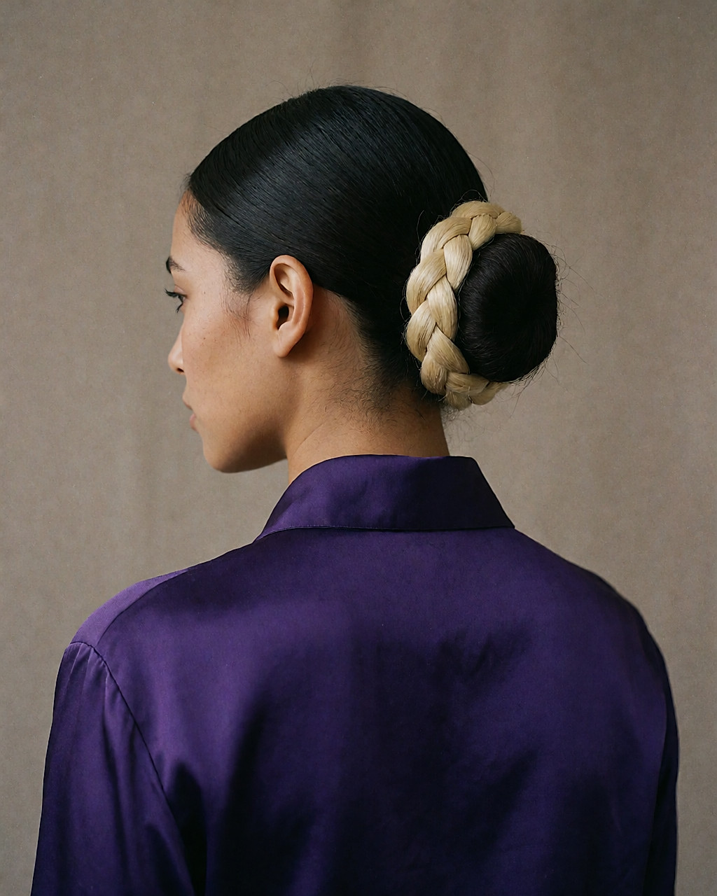 Chignon massif de dos, serti d'une tresse claire, devant tiré et lissé