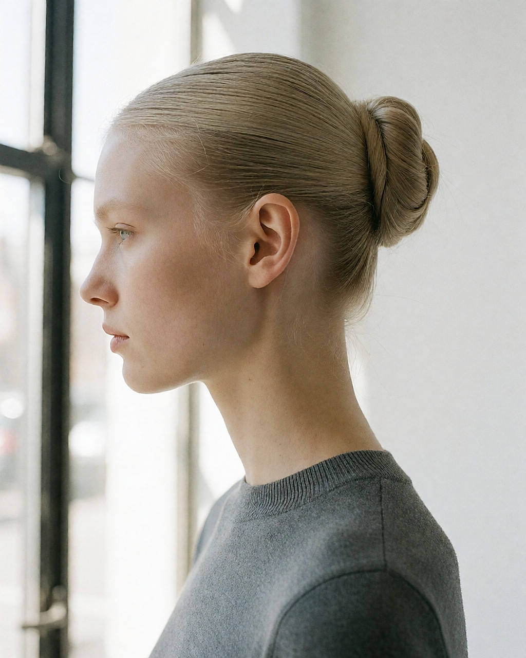 De profil, chignon de ballerine très haut sur la nuque, cheveux lissés et lien extra-fin