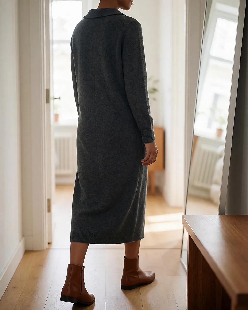 Woman seen from behind in a grey knit straight dress and flat leather ankle boots