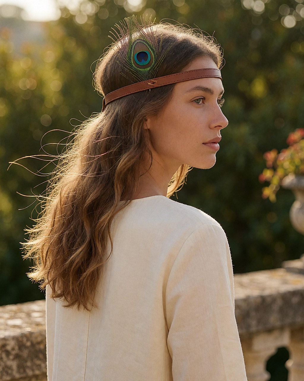 Serre-tête en cuir cognac orné d'une plume de paon, porté en extérieur à l'heure dorée