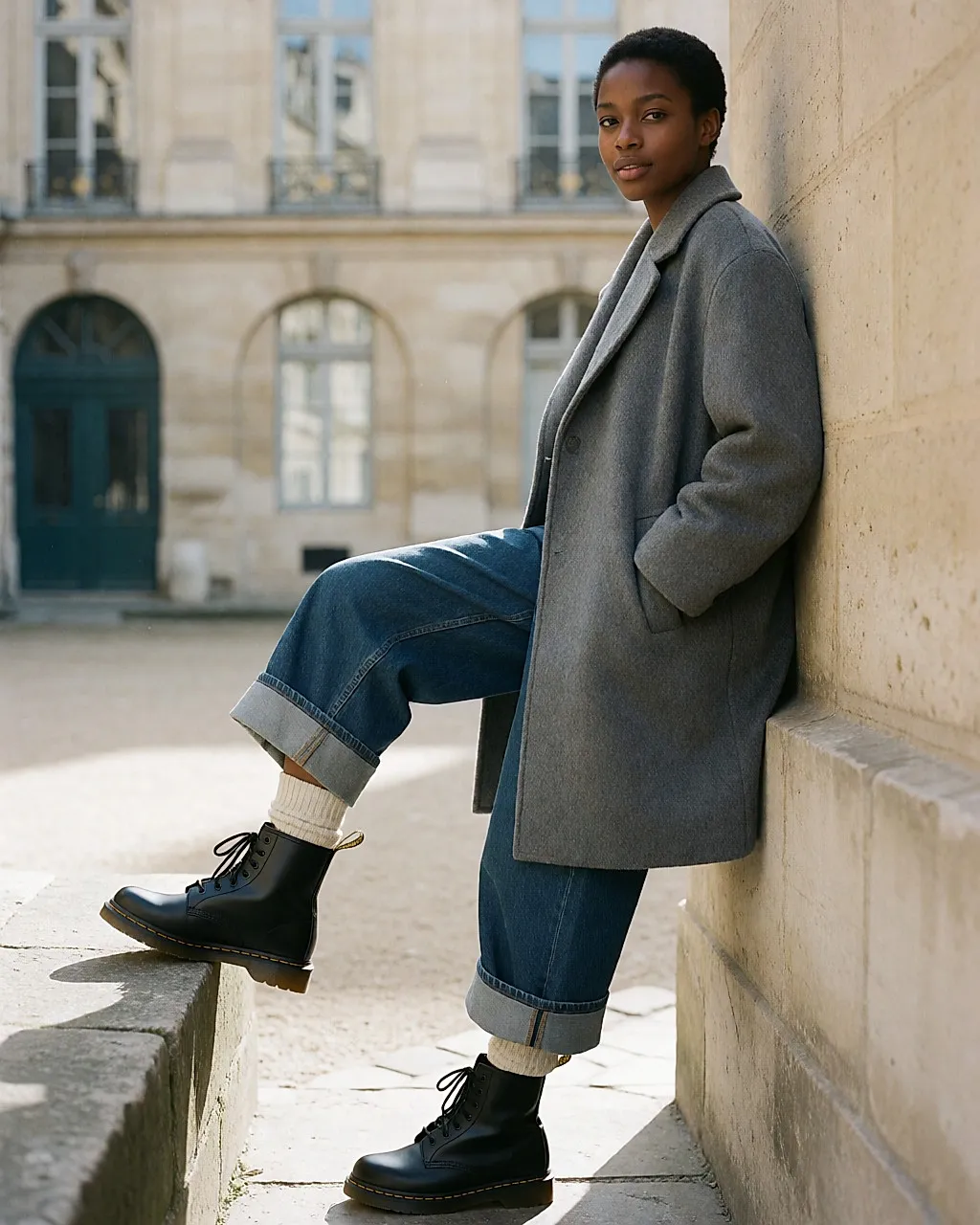 Femme assise ajustant le laçage de ses Dr Martens 1460 noires, jean brut et chaussettes de laine