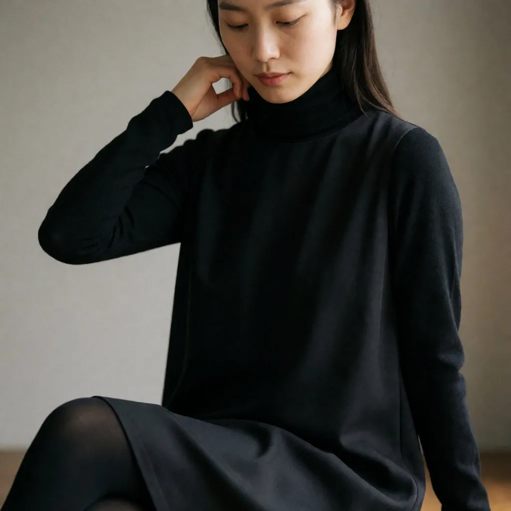 Close-up of a layering detail: a fine wool roll-neck worn under a fluid dress