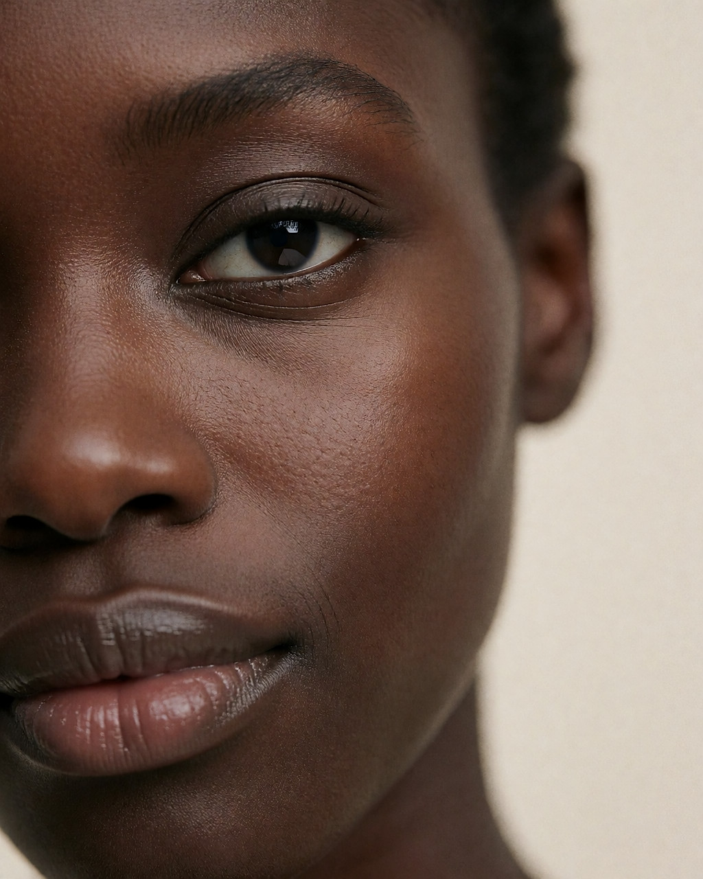 Gros plan sur la peau foncée d'une femme, texture naturelle effleurée par une lumière chaude