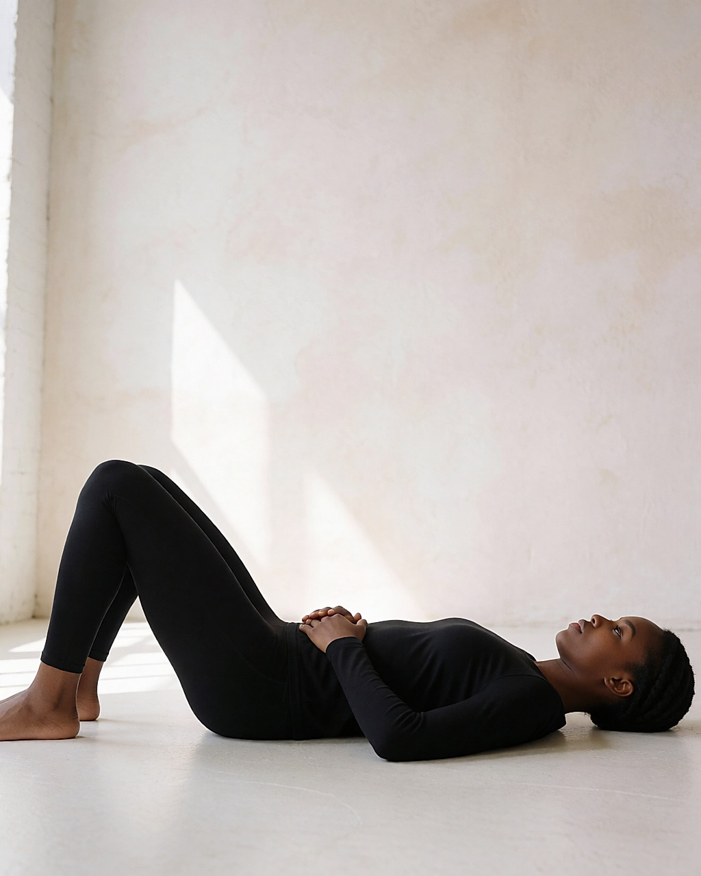 Femme allongée sur un tapis, genoux fléchis, main posée sur le ventre pour sentir le travail des muscles profonds
