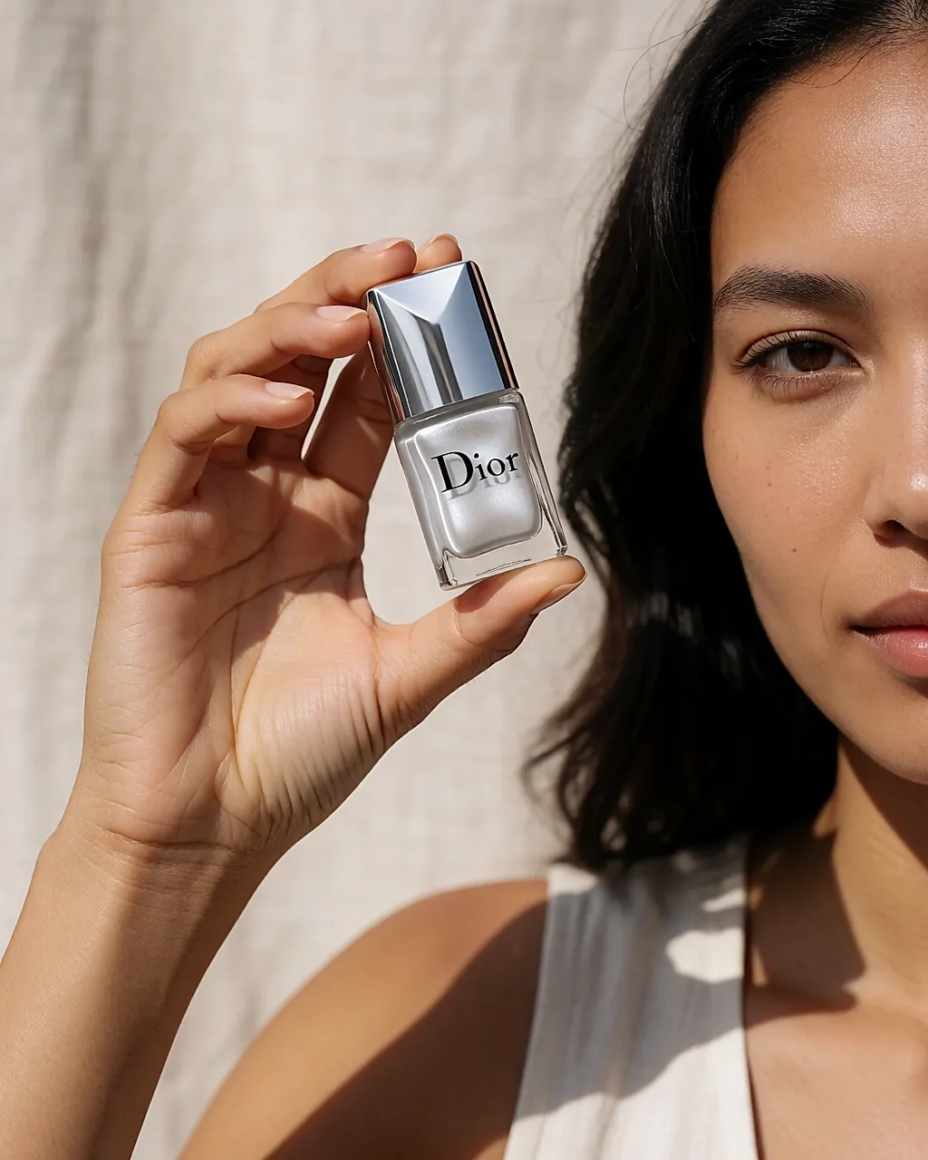 Flacon de vernis gris perle nacré de Dior tenu dans une main
