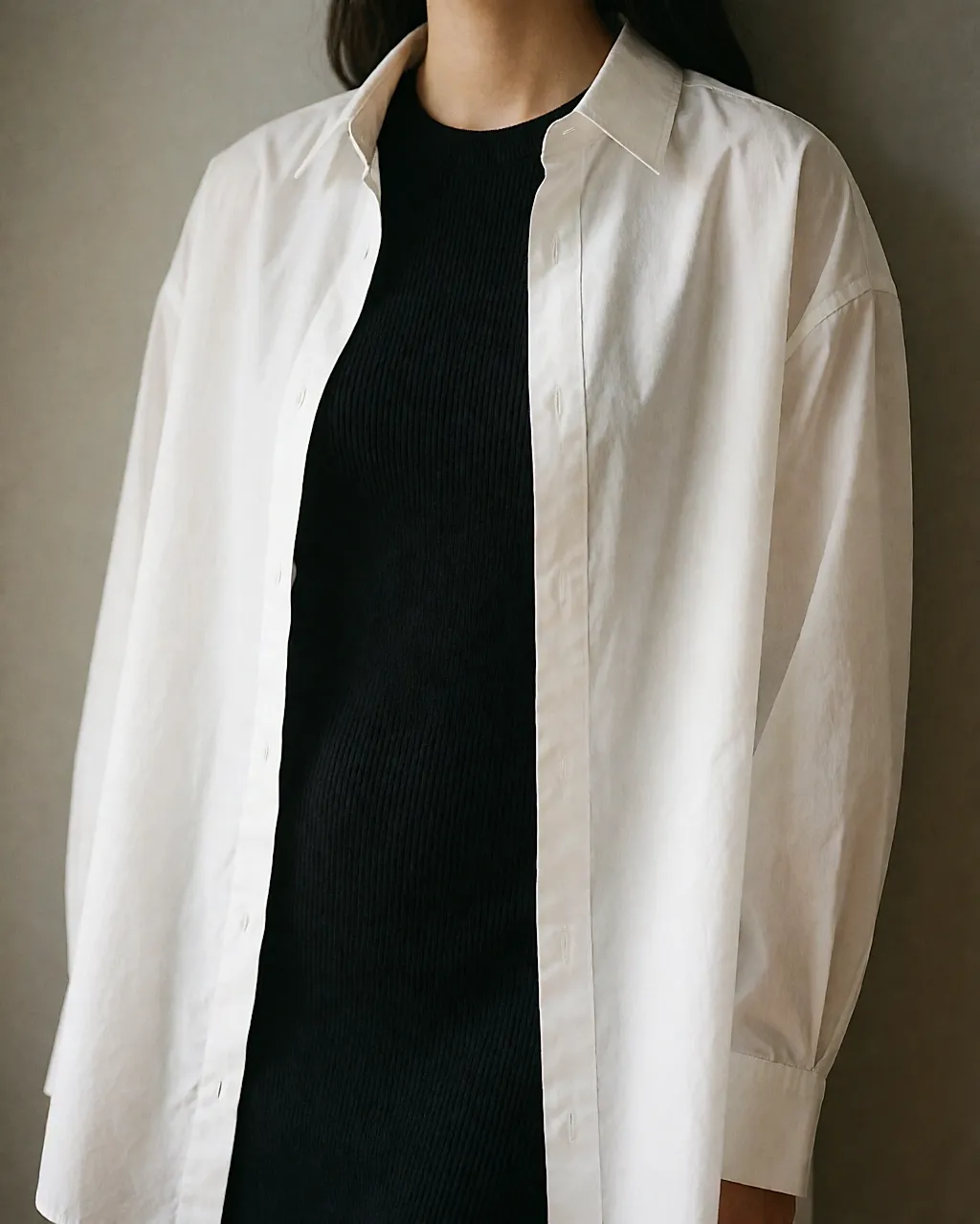 Close-up of the torso: open white shirt over a black knitted dress