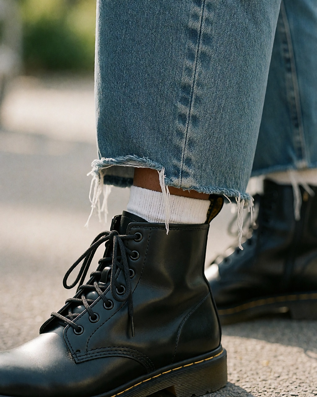 Détail d'un ourlet de jean effiloché porté sur une botte en cuir noir