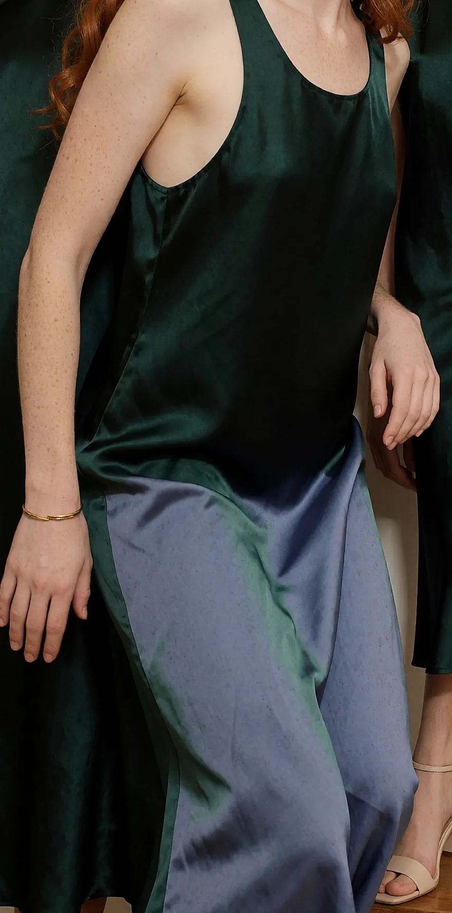 Jovem mulher de pele clara e cabelo ruivo com vestido de cetim verde esmeralda