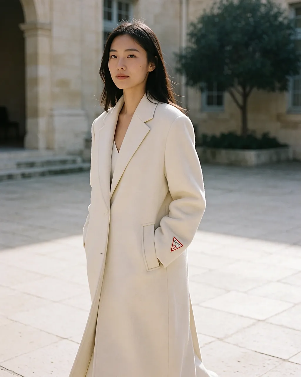 Pristine long Guess wool coat worn in a stone courtyard in winter