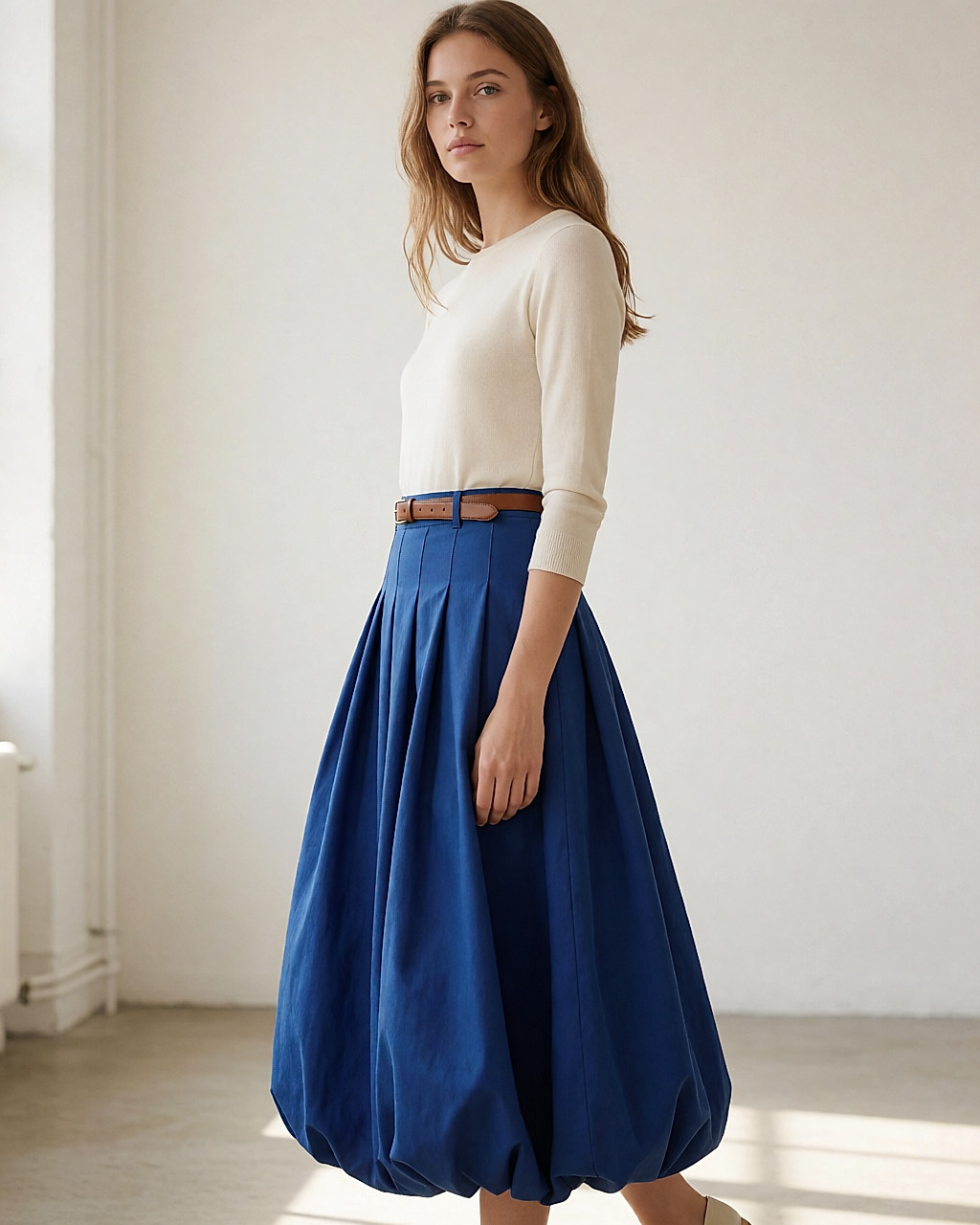 Silhouette avec jupe ballon bleu cobalt volumineuse et haut crème ajusté rentré à la taille
