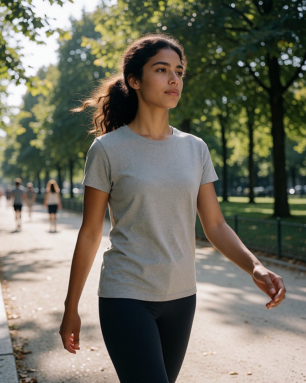 Jeune femme marchant d'un pas rapide sur une allée de parc arborée au petit matin