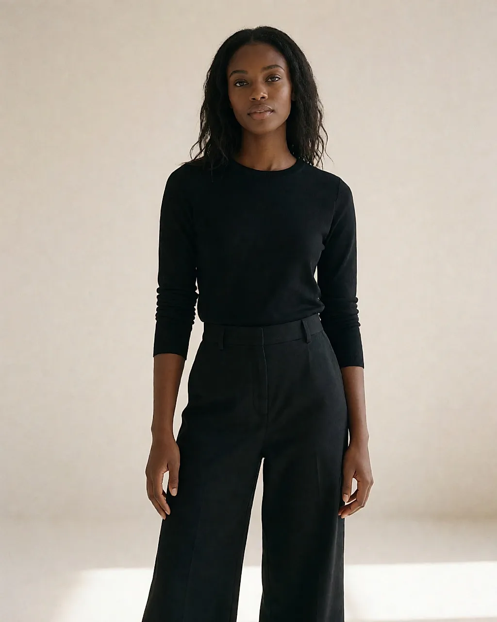 A matching black set worn in studio: fitted top and wide-leg trousers in organic cotton
