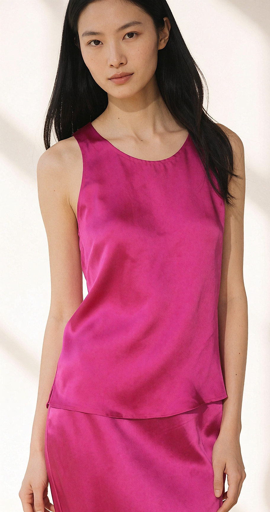 Portrait mi-corps d'une jeune femme portant une blouse en soie fuchsia, lumière naturelle douce