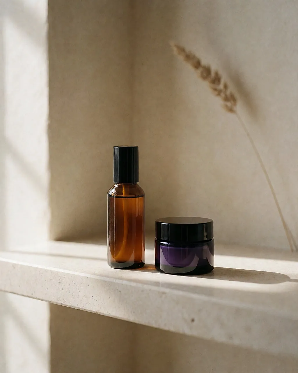 Bernsteinfarbenes Serumfläschchen und kleiner, markenloser Retinol-Tiegel nebeneinander auf einem steinernen Regal.
