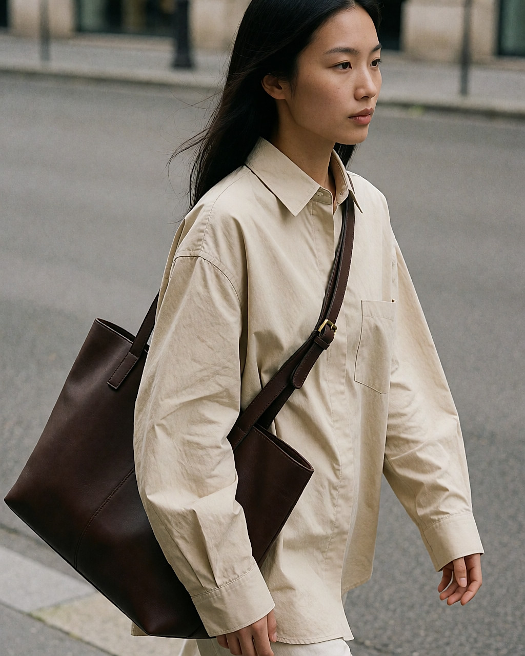 Jeune femme portant un sac lourd en bandoulière, la sangle appuyée en travers de la poitrine