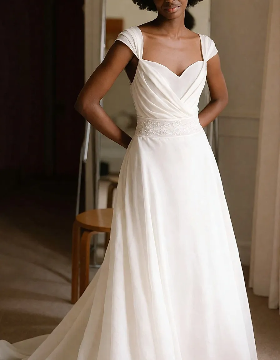 Novia con vestido de muselina de bustier drapeado y escote corazón frente a un espejo