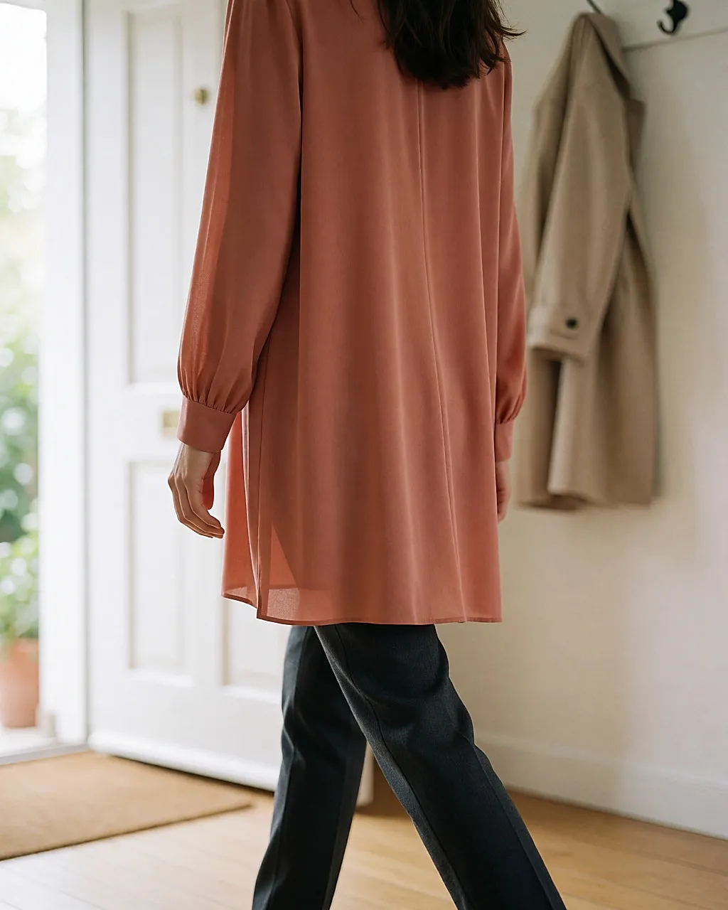 Terracotta tunic seen from the back, fluid hem over anthracite trousers