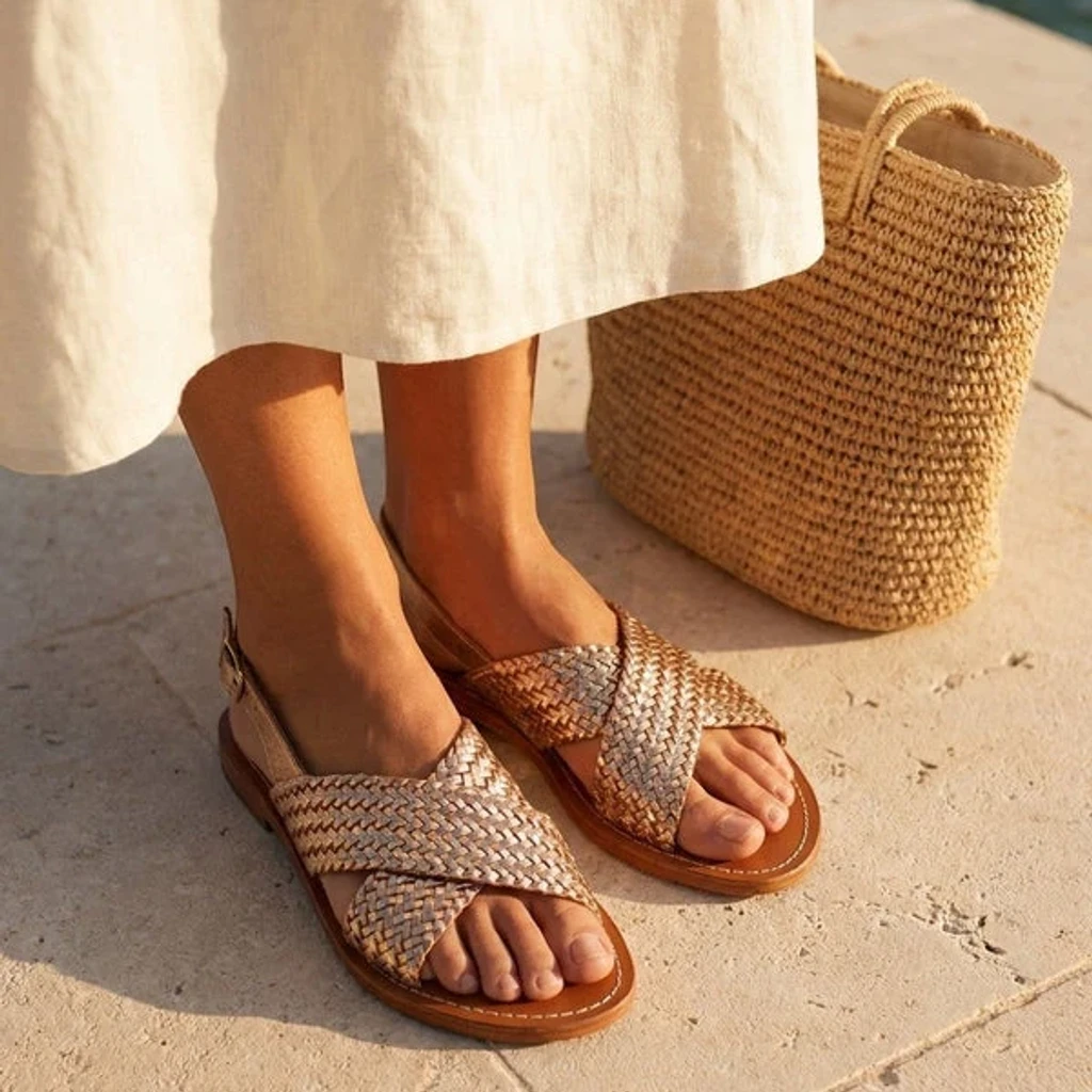 Feine goldene Sandalen auf hellem Steinboden